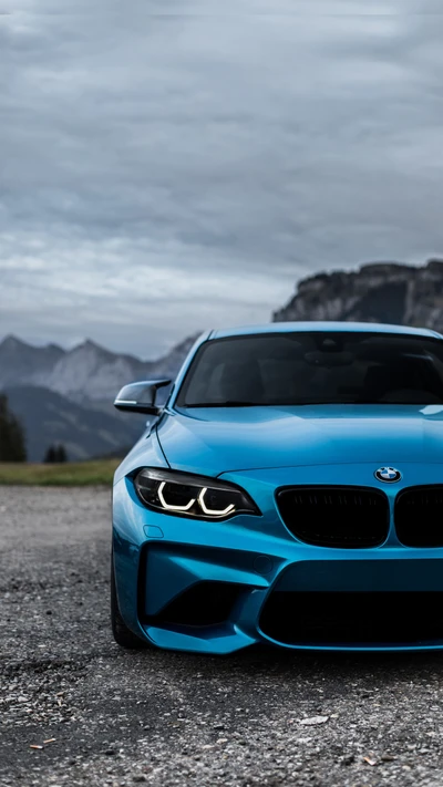 Auffälliger BMW M2 F87 Coupé in atemberaubendem Blau, vor einer dramatischen Bergkulisse.