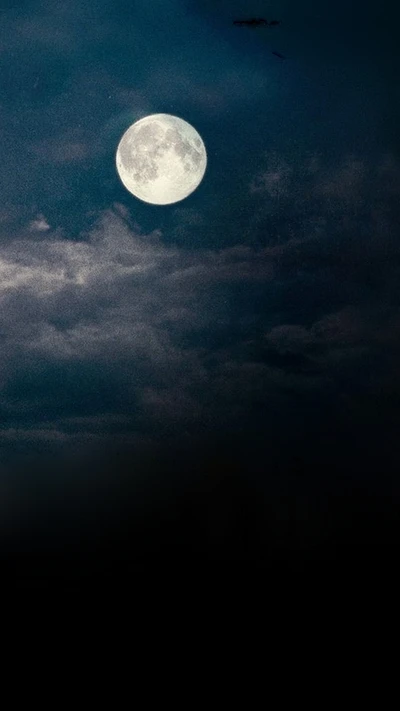 Majestuosa luna llena iluminando un cielo nocturno nublado