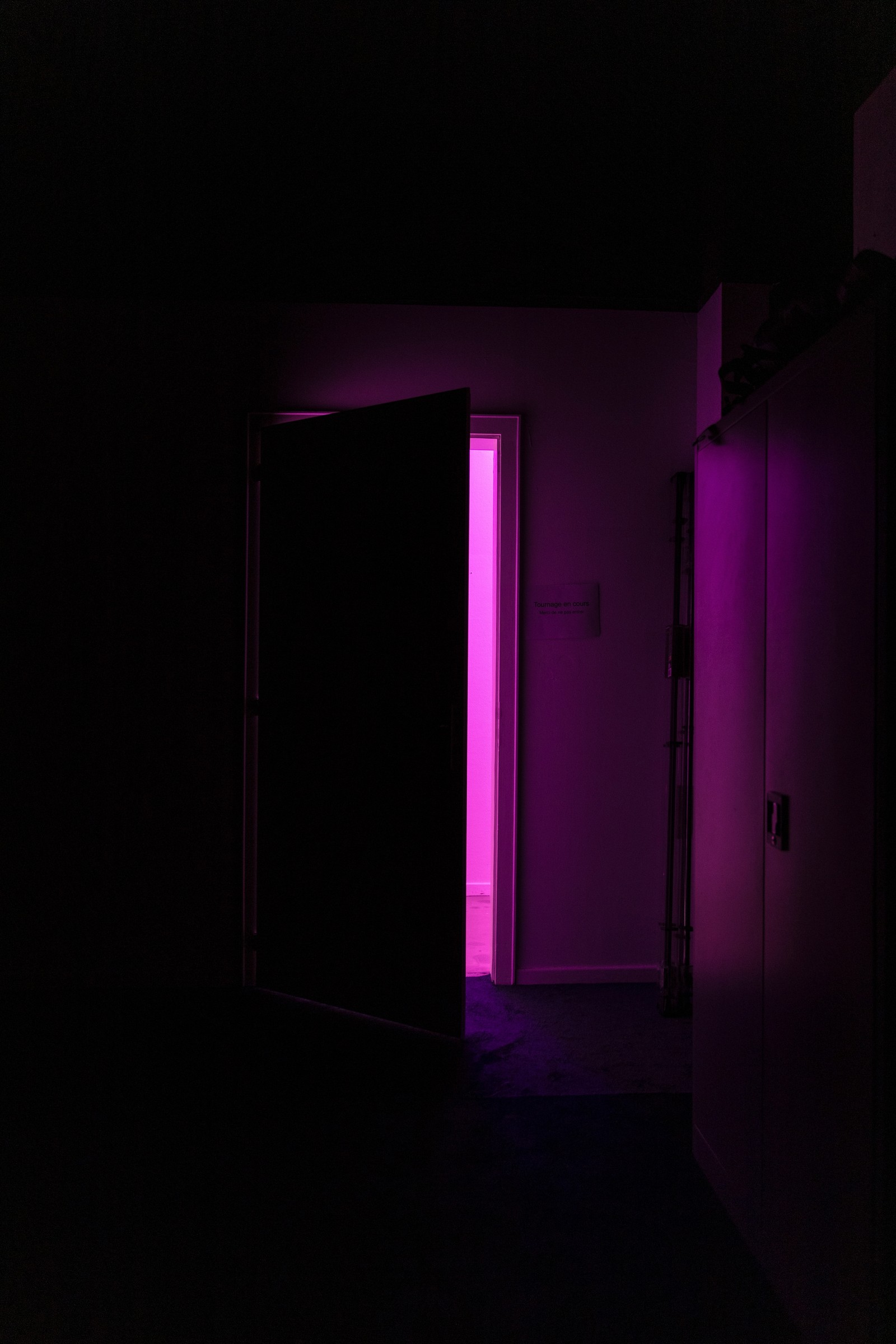 Une lumière violette brille dans une pièce sombre avec une porte ouverte (obscurité, violet, chambre, éclairage, lumière)