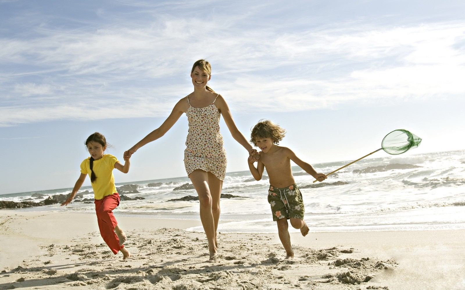 There are two children running on the beach with a net (beach, fun, vacation, summer, sand)