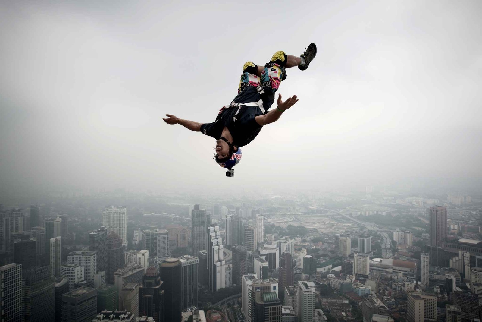 Un hombre árabe haciendo un truco en una patineta en el aire (kuala lumpur, saltando, deporte extremo, base jumping, especialista)