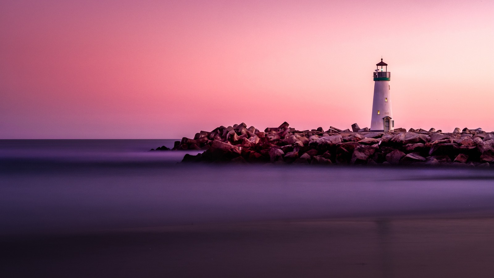 Um farol em uma ilha rochosa com um céu rosa (farol, mar, horizonte, torre, oceano)