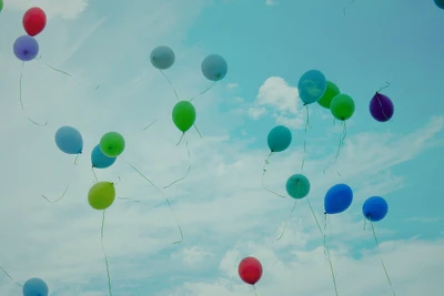 Des ballons colorés flottant contre un ciel bleu