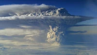 Majestic volcanic eruption under a serene sky, with towering cumulus clouds and a tranquil atmosphere.