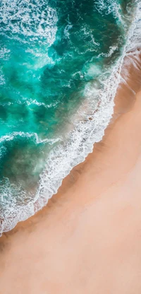 Vue aérienne d'une plage sereine avec du sable doré doux, des vagues turquoise qui viennent doucement s'échouer sur le rivage, et un arrière-plan de nuages légers.