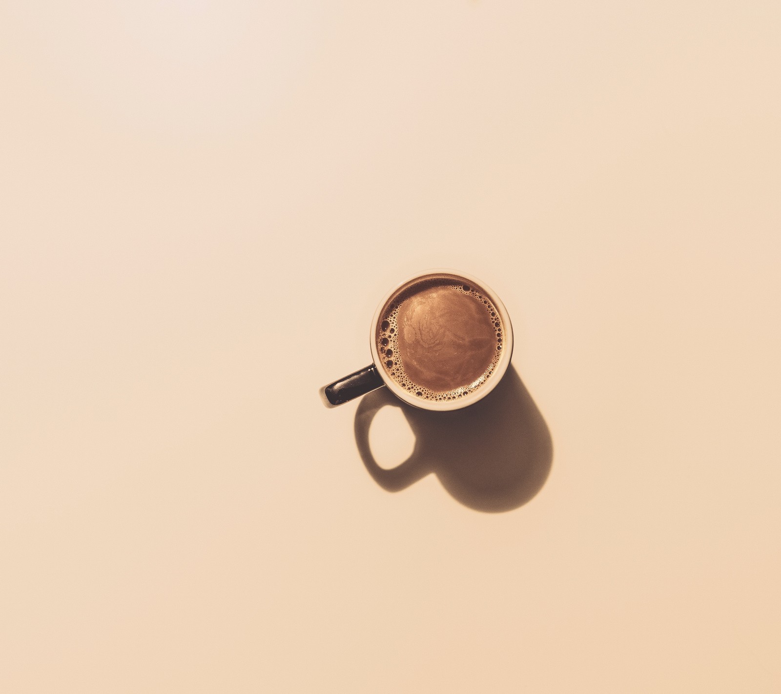 Eine tasse kaffee steht auf einem tisch mit einem schatten (braun, kaffee, tasse, montag)