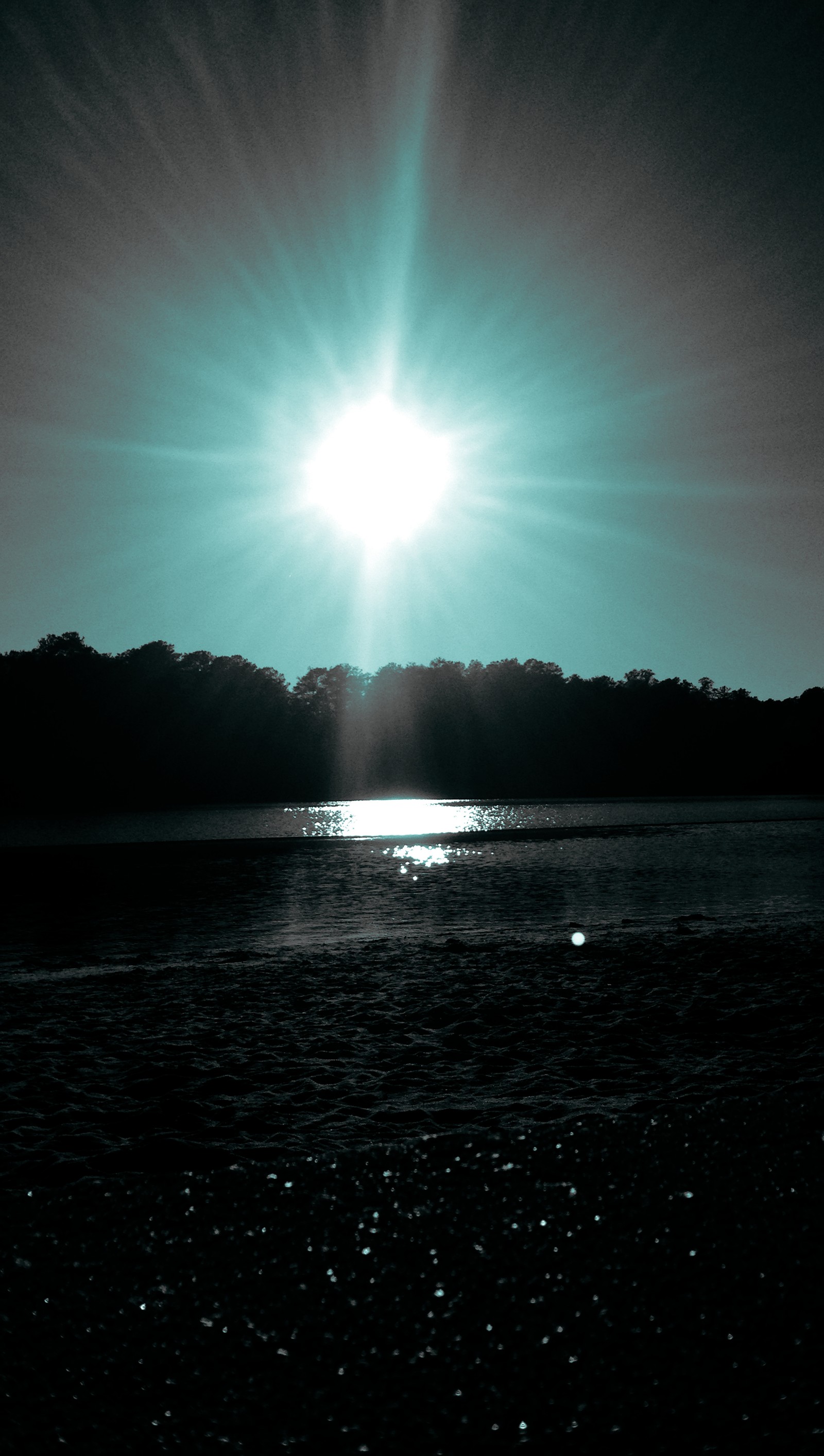 Arafed view of a sun shining over a body of water (beach, black, blue)