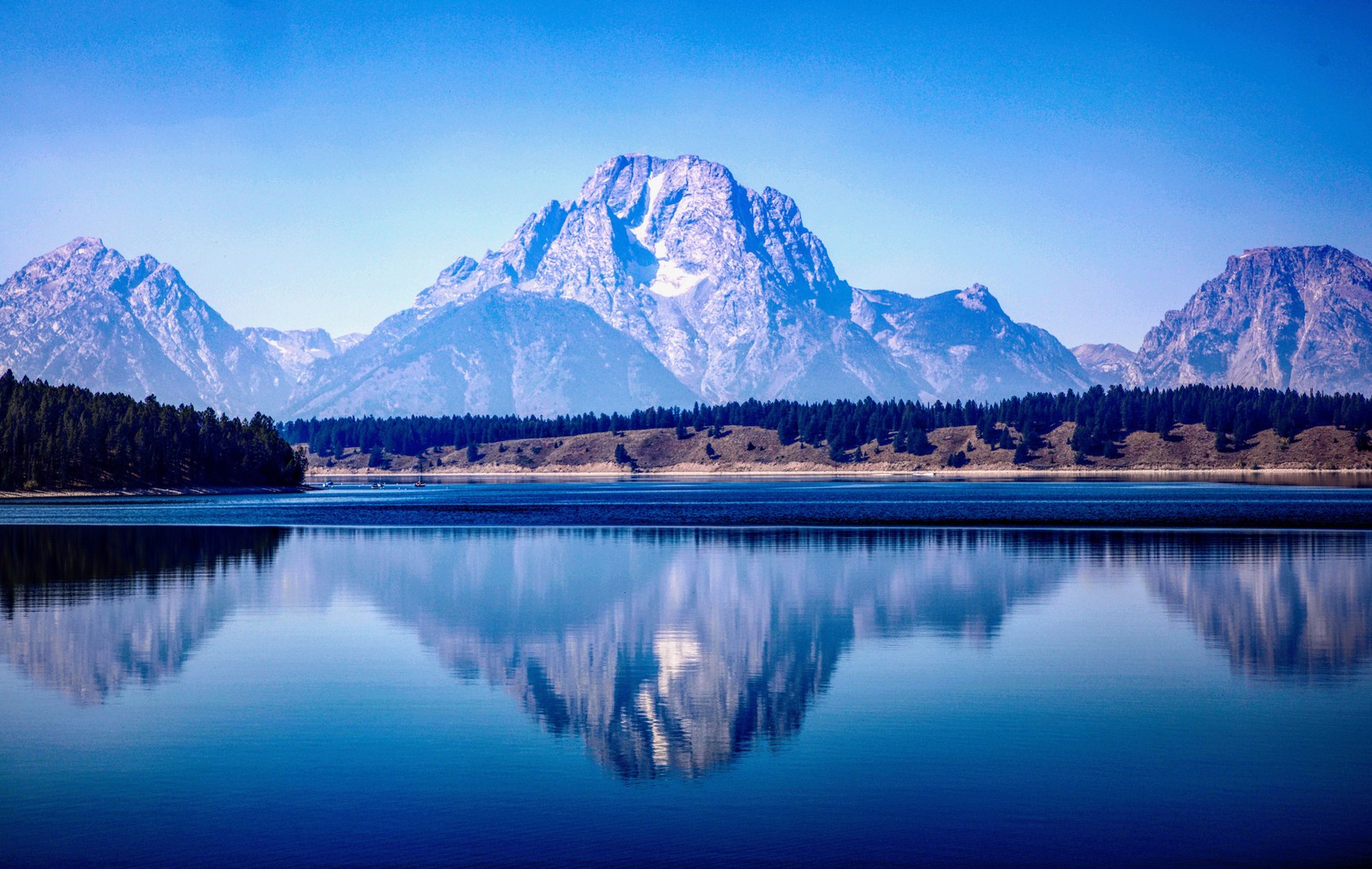 Eine aussicht auf ein gebirgsmassiv mit einem see im vordergrund (grand teton nationalpark, gebirgskette, see, reflexionen, blau)