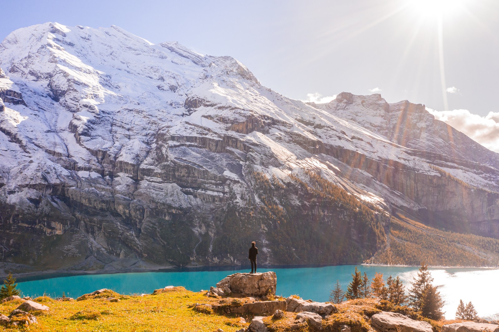 Arafed person standing on a rock overlooking a mountain lake (sky, nature, glacial lake, fjord, glacier)