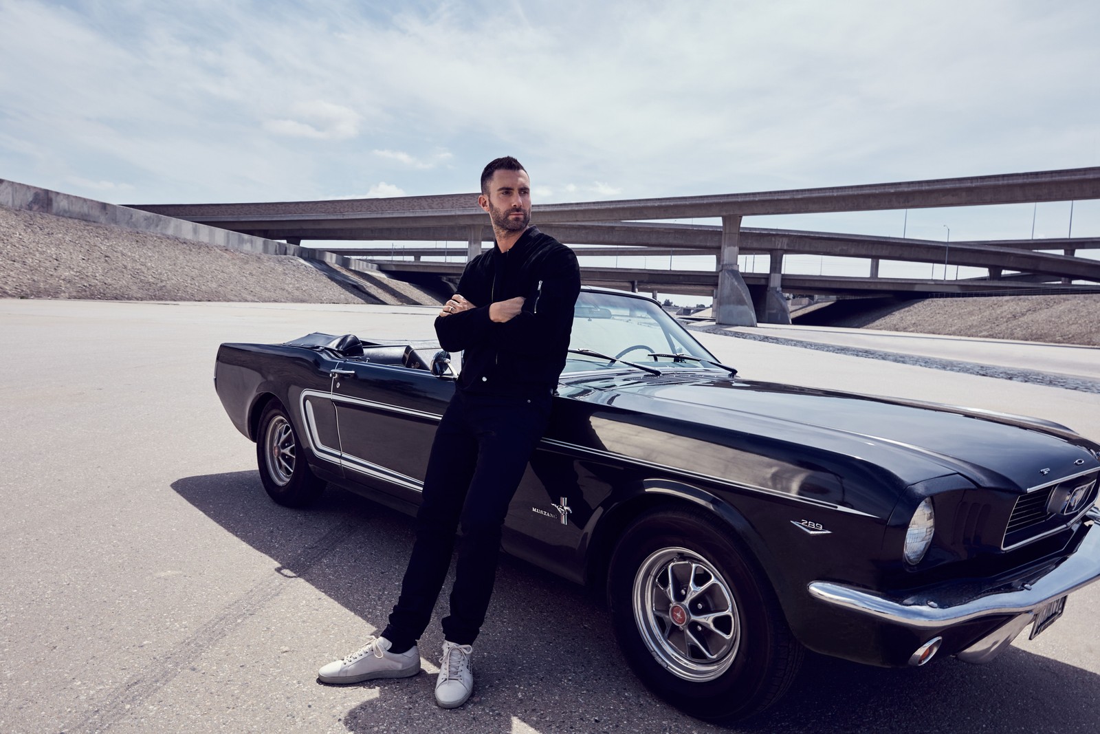 Arafed man standing next to a classic mustang car in a parking lot (car, muscle car, classic car, sedan, singer)