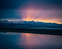 Majestoso amanhecer sobre a cordilheira coberta de neve refletindo em águas tranquilas perto de Salt Lake City.