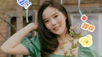 Hyojung d'Oh My Girl rayonne de joie, tenant des fleurs et entourée de gribouillis colorés et ludiques.