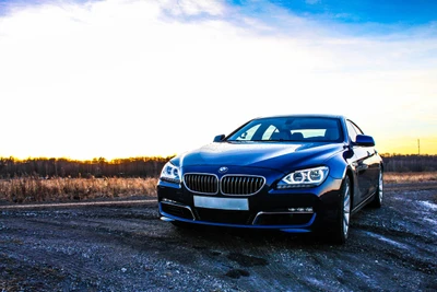 Luxuriöses BMW 6er Sportauto vor einem lebhaften Sonnenuntergangshimmel.