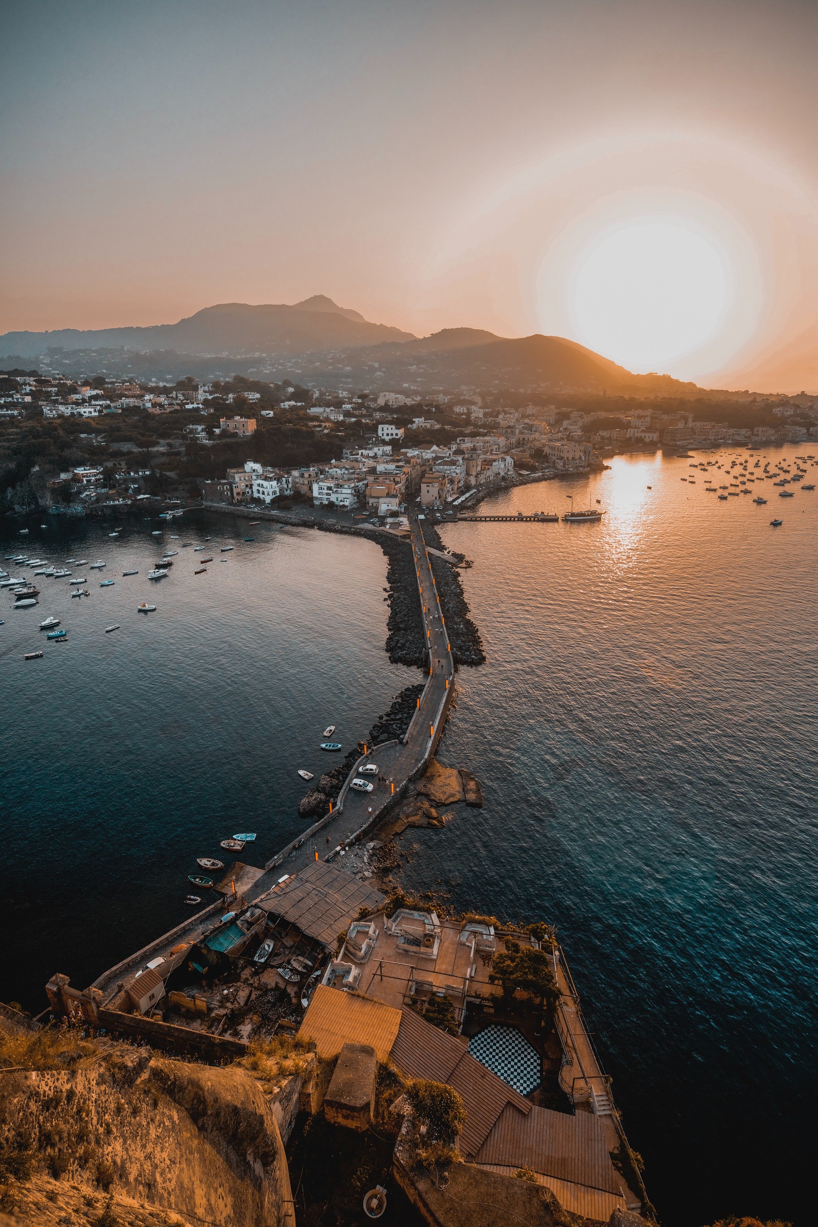 Vista aérea de um porto com barcos e um pôr do sol (por do sol, água, recursos hídricos, mar, costa)