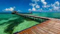 Píer tropical com vista para uma lagoa azul sob um céu brilhante