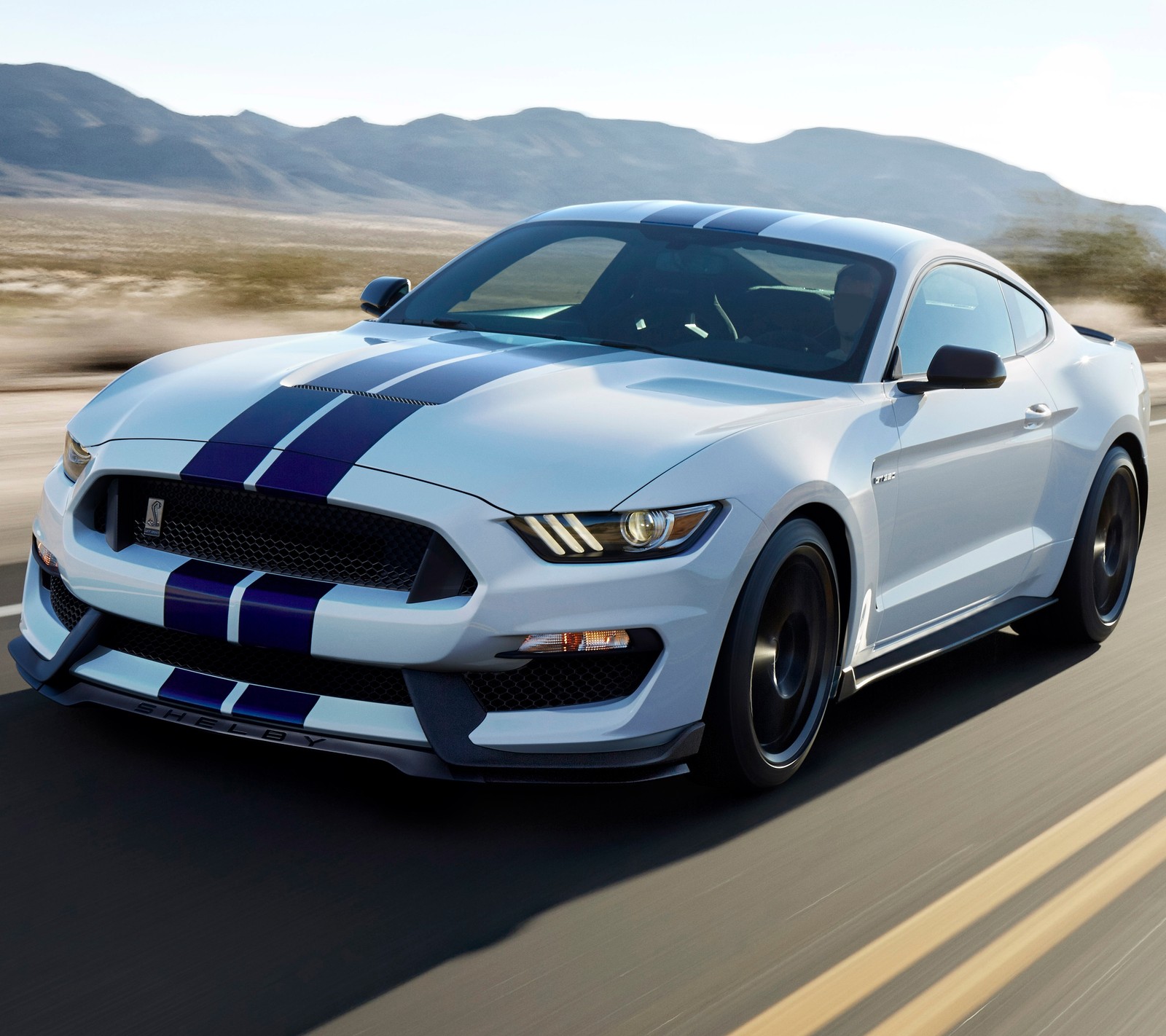 Um mustang branco dirigindo por uma estrada com montanhas ao fundo (carro, ford, mustang, estrada, shelby)