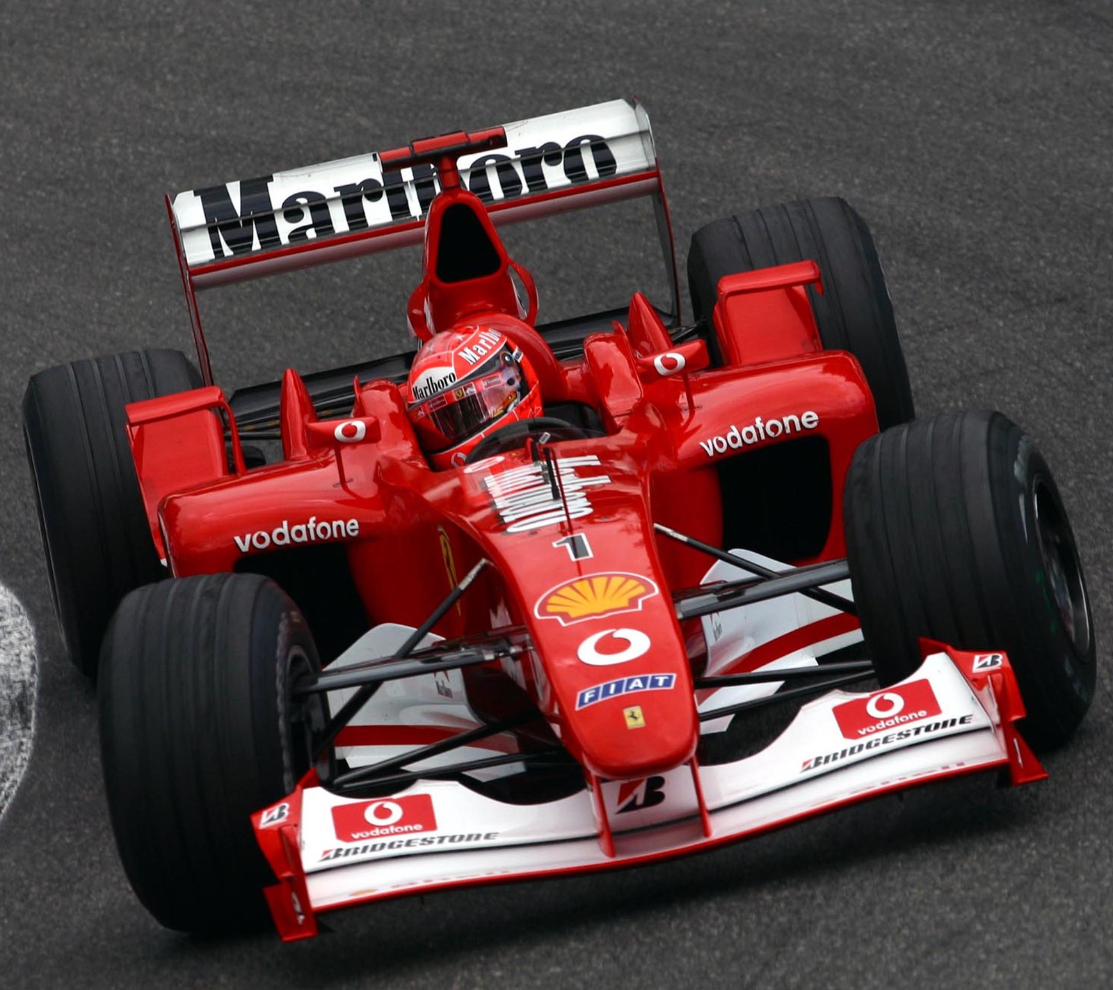 Arafed ferrari racing car on a track with a number of tires (driver legend, f1, ferrari, michael, racing)