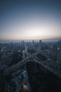 Um horizonte urbano de tirar o fôlego ao anoitecer, exibindo uma metrópole em expansão com arranha-céus e uma rodovia movimentada se cruzando em meio a um horizonte tranquilo.