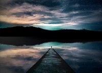 Silueta solitaria al atardecer: reflexiones sobre un lago sereno bajo un cielo estrellado