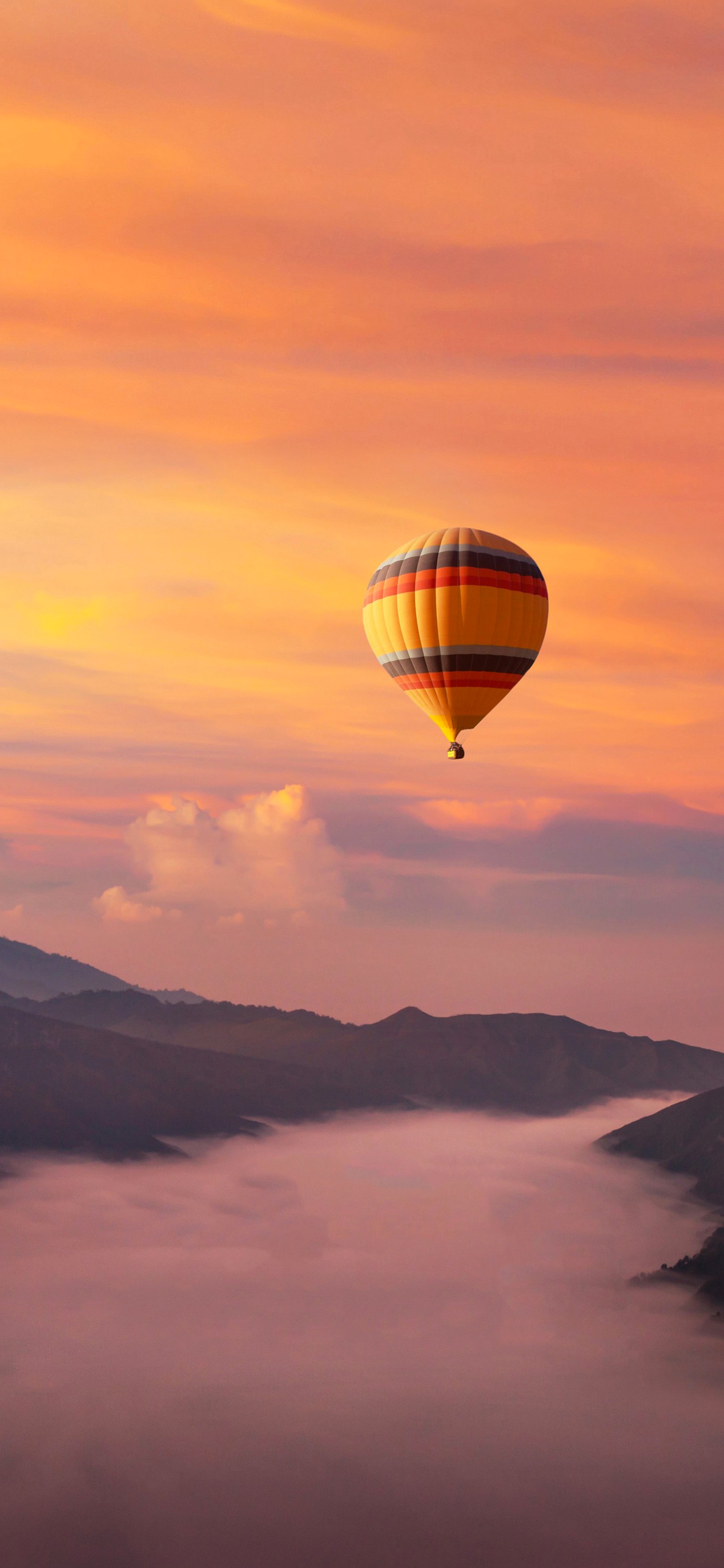 Un ballon flottant au-dessus d'une vallée avec une montagne en arrière-plan (montgolfière, coucher de soleil, ballon, nature, journée)