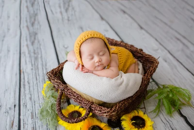 Adorable Newborn in Crochet Yellow Costume Nestled in a Basket Surrounded by Sunflowers