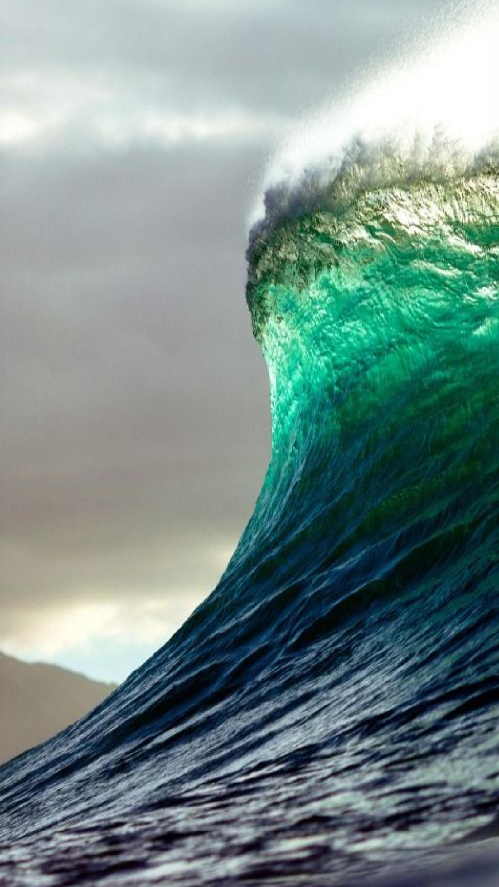 Surfer riding a large wave in the ocean on a cloudy day (jgv, jnhg)