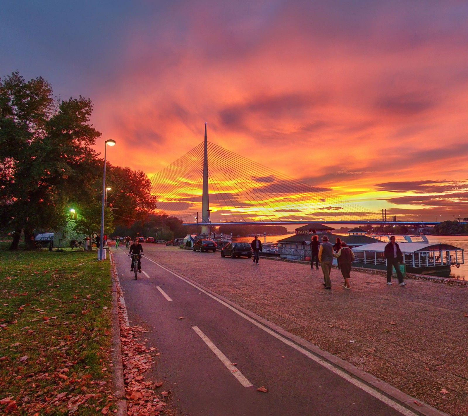 Pessoas caminhando e pedalando em uma trilha perto de um rio ao pôr do sol (abej, beograd, sérvia)