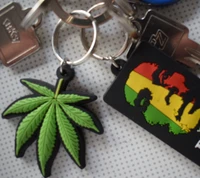 Keychain with a vibrant green marijuana leaf and a colorful Rastafarian-themed card.