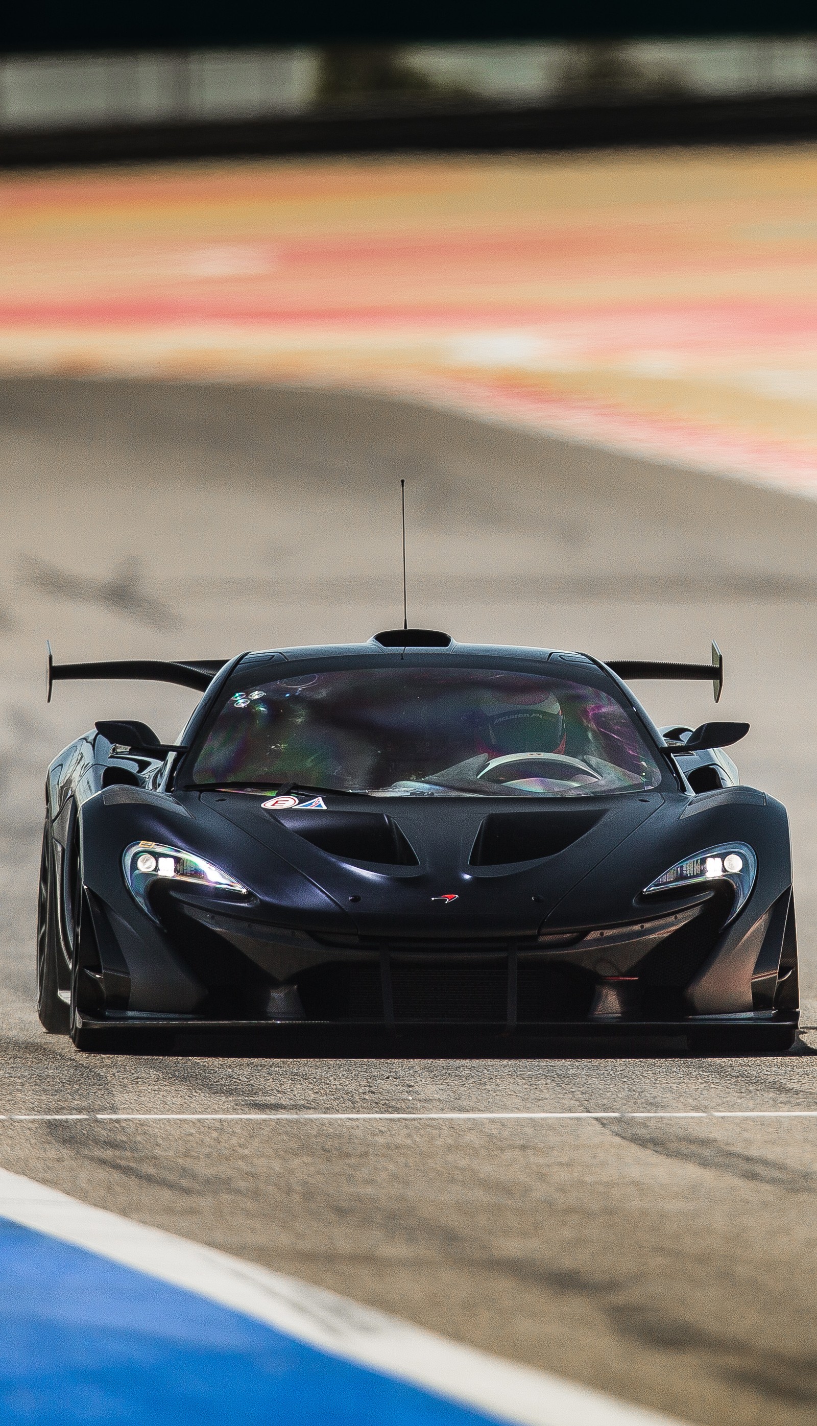 Arafed black sports car driving on a track with a blue and white stripe (car, mclaren, mclaren p1, race, supercar)