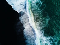 Vista aérea de la playa de arena negra Reynisfjara, olas rompiendo en el océano