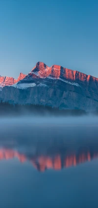 Ruhiger Dämmerung über dem azurblauen Hochlandsee und majestätische Bergreflexionen