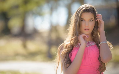 Elegantes Porträt eines blonden Models mit langen Haaren in einem rosa Kleid