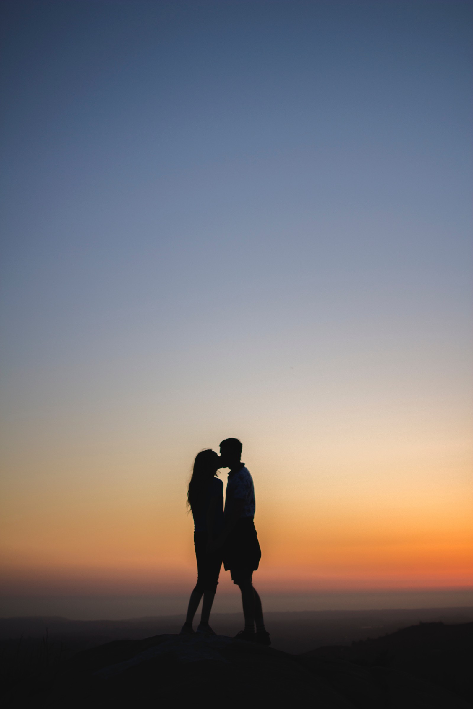 Arafed couple kissing on a hill at sunset (silhouette, romance, kiss, couple, people in nature)