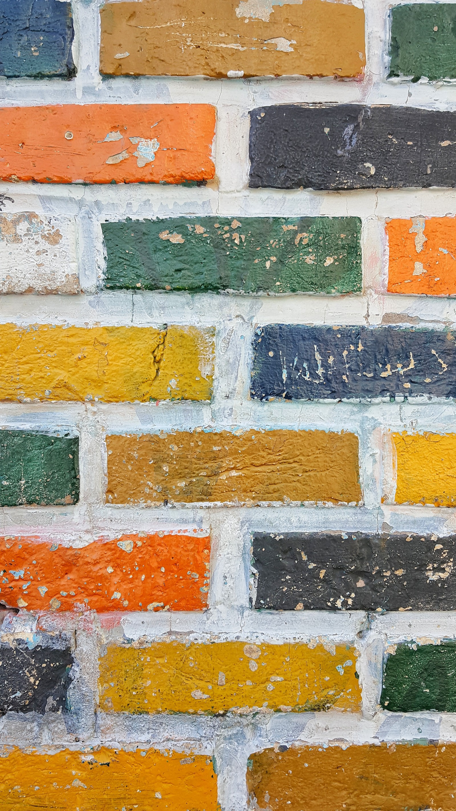 Primer plano de una pared de ladrillos con un hidrante en frente (ladrillo, pared, naranja, amarillo, mampostería)