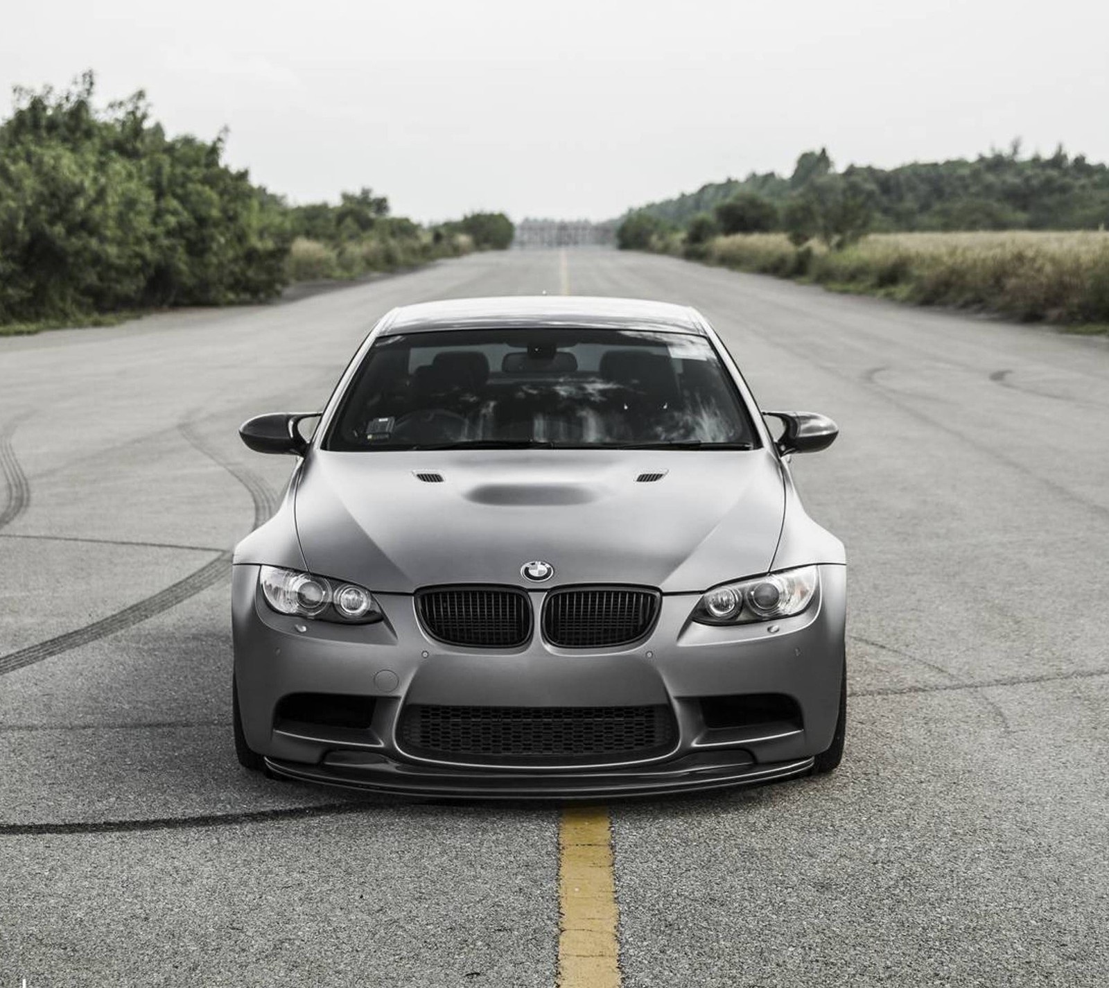 A close up of a car parked on a road near a field (bmw, car, grey, road)