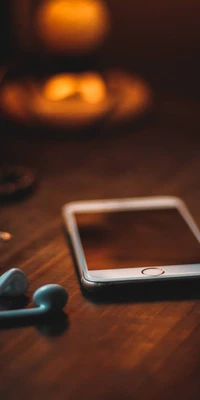 iPhone on a wooden surface with earphones and a blurred warm background.