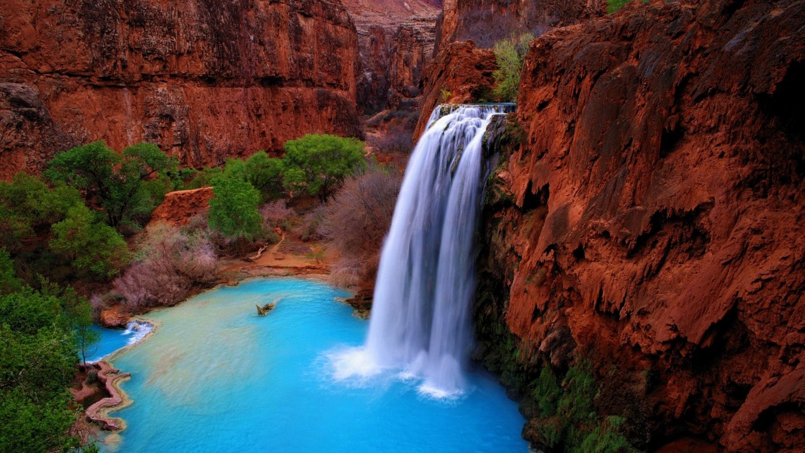 A waterfall in the middle of a canyon with a blue pool (grand canyon, supai, waterfall, body of water, water resources)