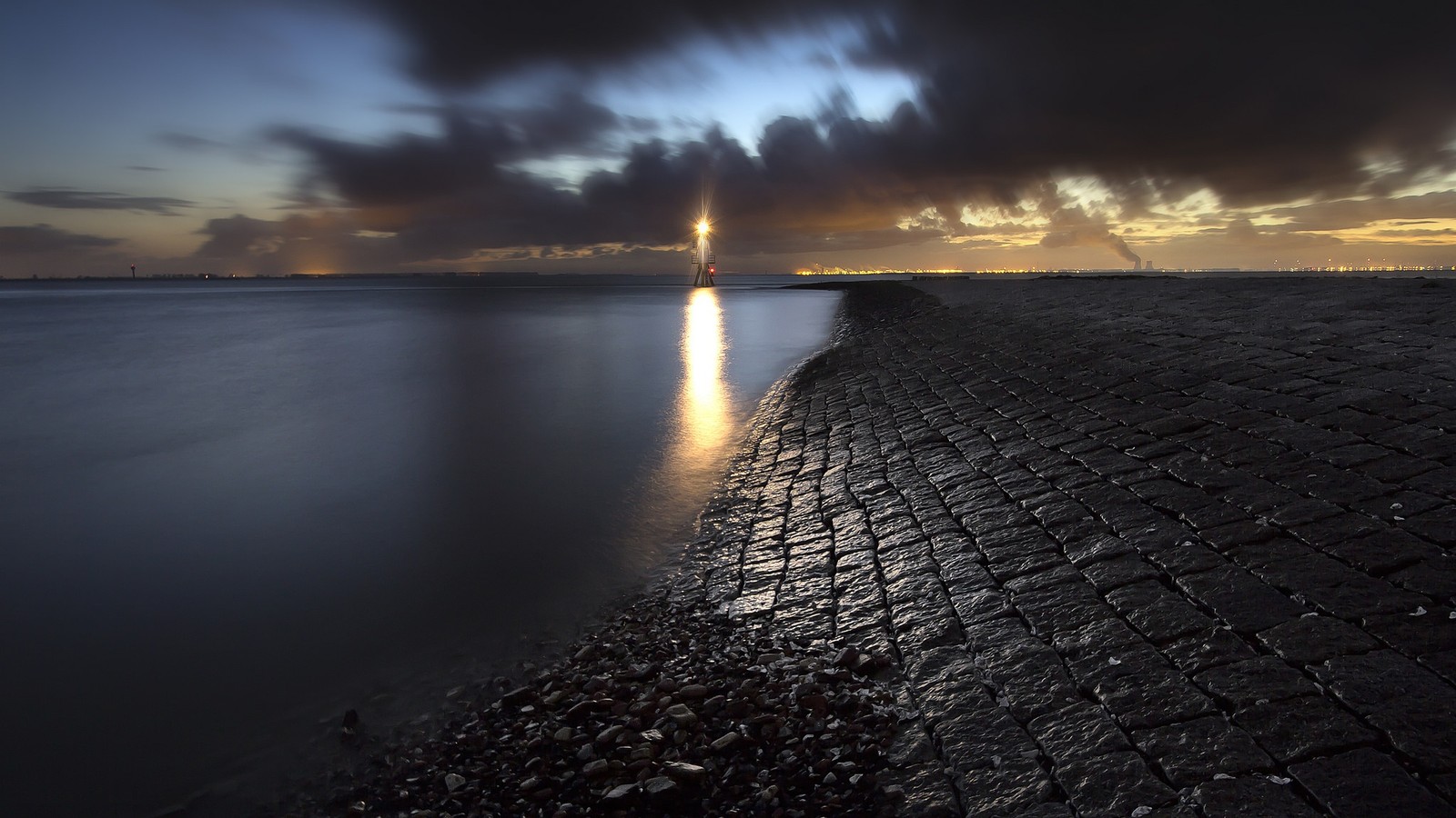 Une vue d'un phare sur une plage rocheuse au coucher du soleil (eau, géométrie, mathématiques, nuage, ressources en eau)