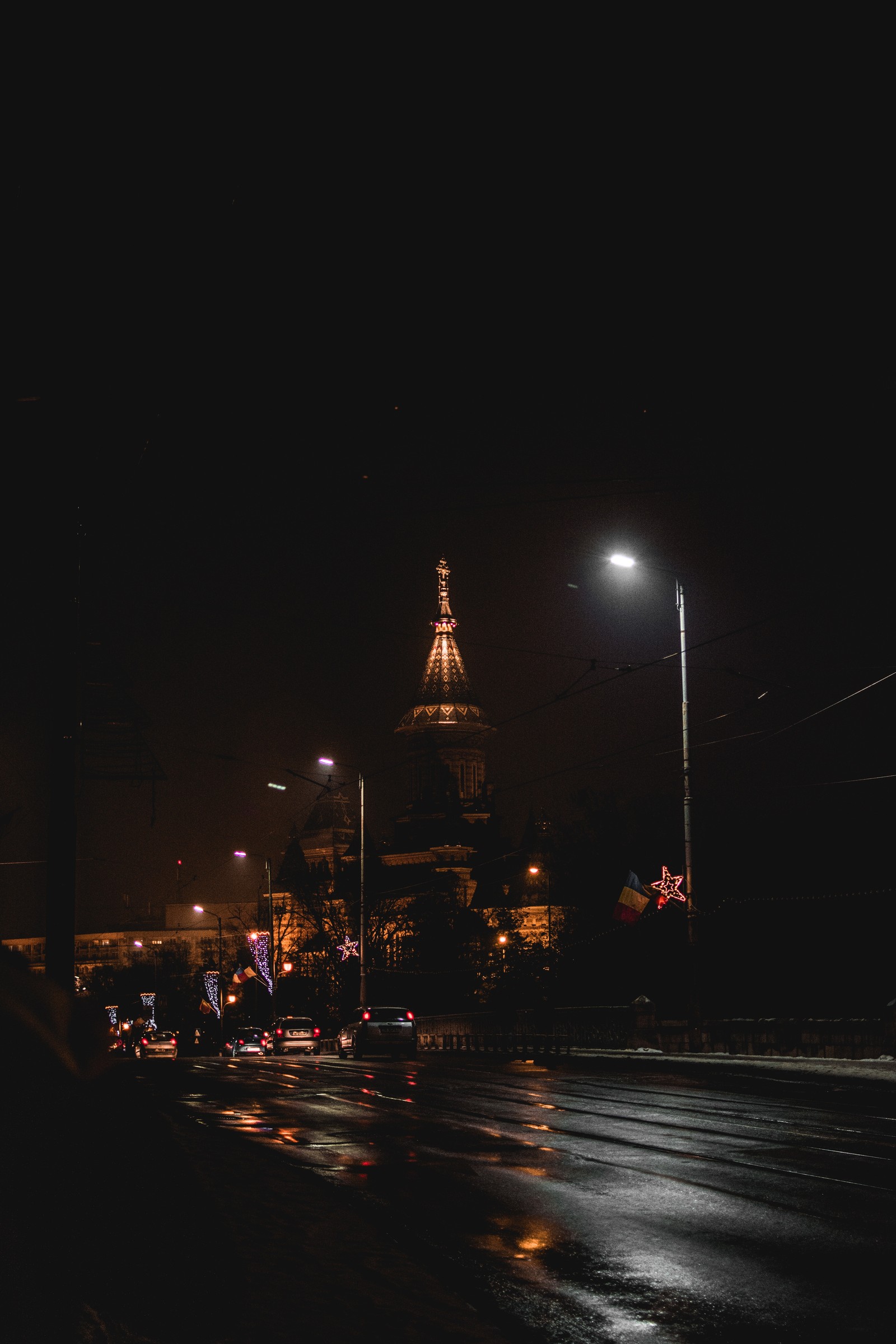 Vista nocturna de una calle de la ciudad con una torre del reloj al fondo (noche, electricidad, farola, atracción turística, área urbana)