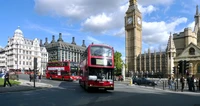 Double-decker buses pass by Big Ben and the Palace of Westminster in vibrant London.