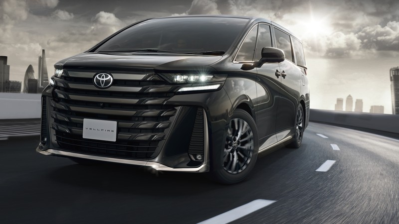 Чёрный toyota sienna едет по шоссе с городским горизонтом на заднем плане. (toyota vellfire, люксовые автомобили, 2023, 5k, машины)