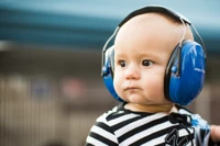 Infant Wearing Protective Headphones in a Safety Seat