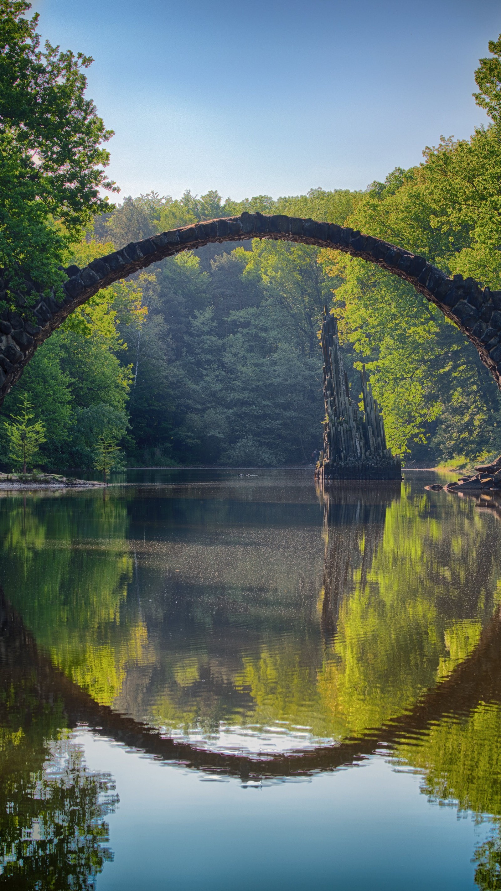 Un pont en pierre sur un lac dans les bois (pont, eau, plante, ressources en eau, nature)