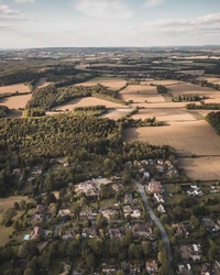 Vista aérea de uma paisagem suburbana cercada por campos e florestas exuberantes