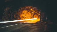 Túnel iluminado à noite com faróis automotivos