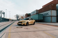 Luxuriöser BMW M4 parkt zwischen Versandcontainern.