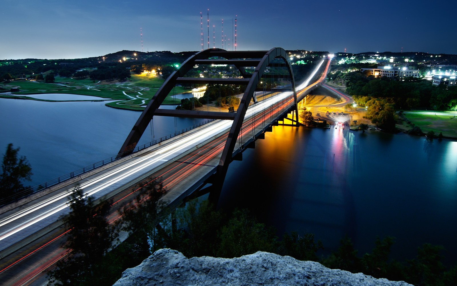 Luftaufnahme einer brücke über einen fluss mit einer stadt im hintergrund (brücke, nacht, wasser, fluss, reflexion)