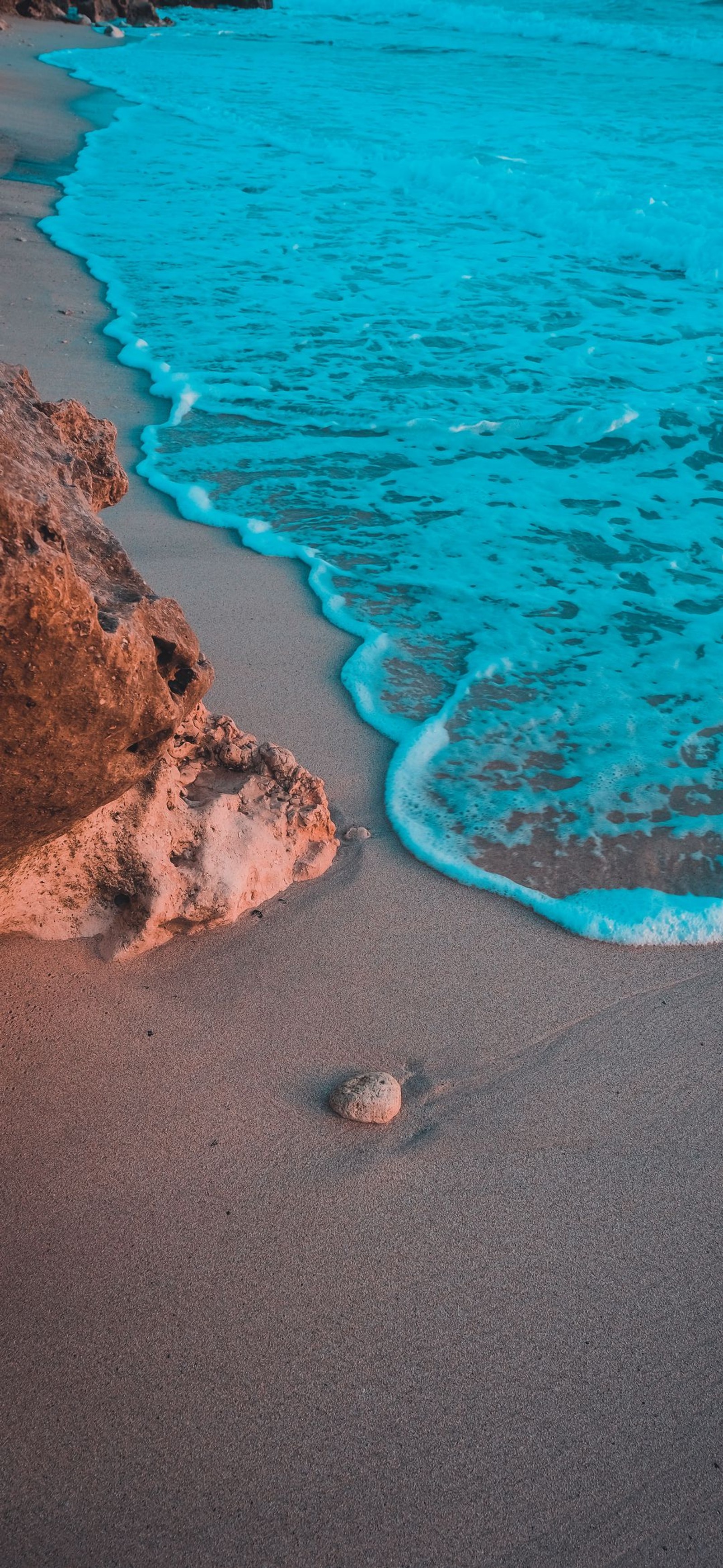 Arafed rock on the beach with a blue ocean in the background (sea, water, ocean, sand, azure)