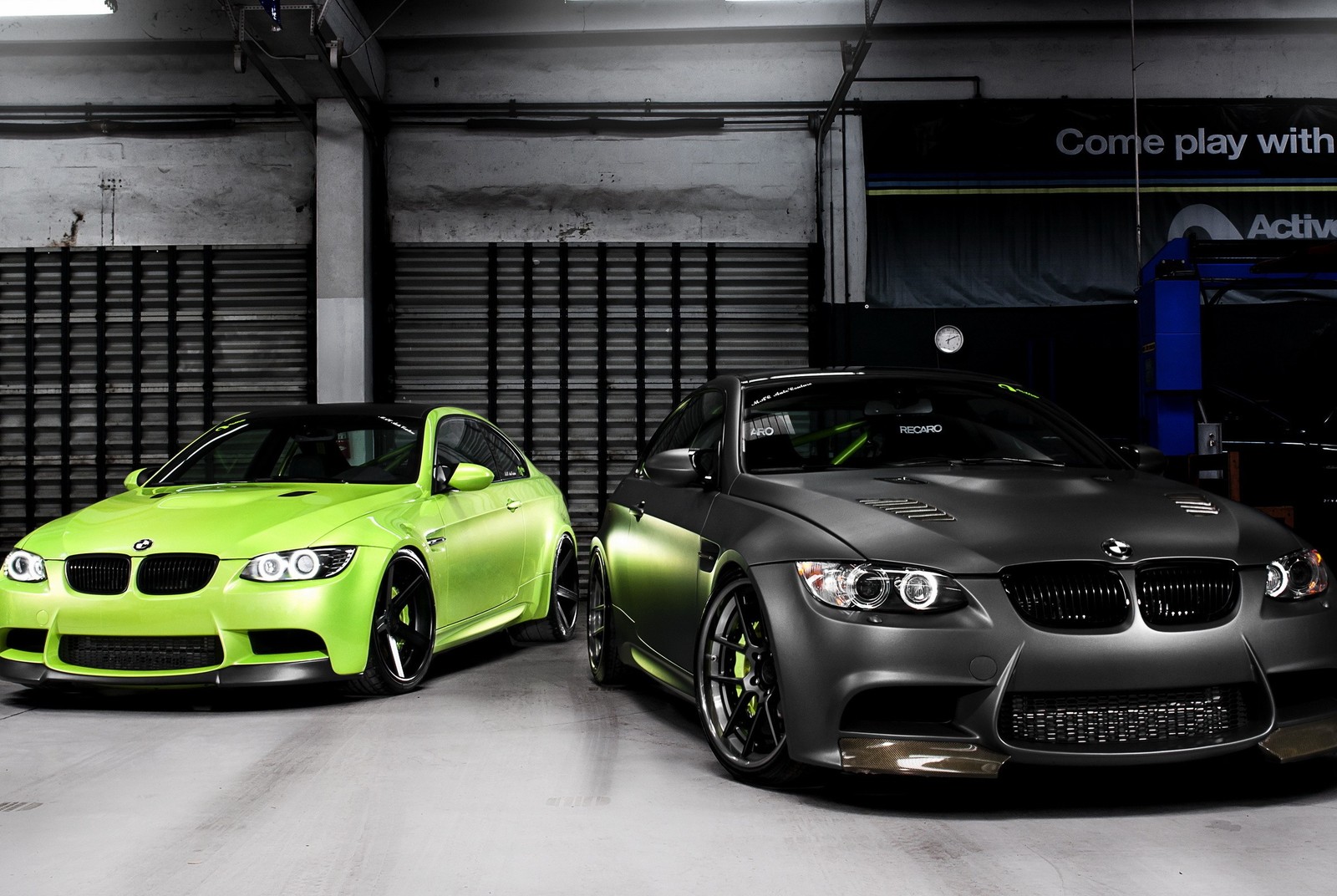 Two cars are parked in a garage with a green car (bmw, cars)