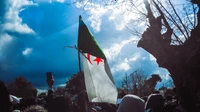 A bandeira argelina agita-se em meio a um protesto lotado por liberdade